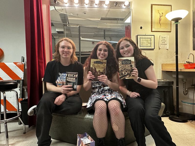 Backstage in a dressing room: Kylee and two friends holding up books