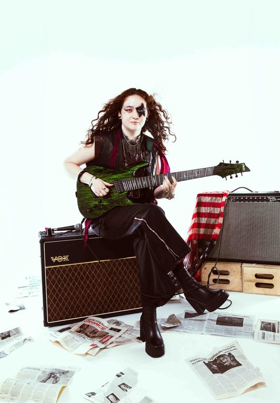 RED STATE promo shot: Kylee seated on a Vox amp in star face paint